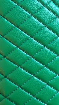Green artificial leather surface texture, stitched in the form of rhombuses, squares, rectangles. Quilted eco-leather. High quality photo