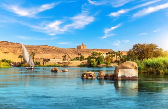 Nile riverbank near Aswan and traditional sailboat, Upper Egypt.