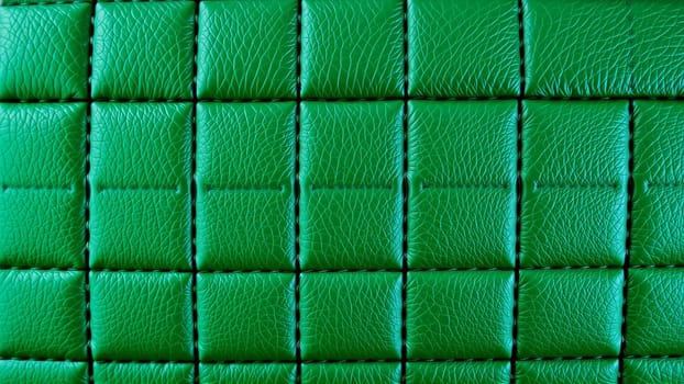 Green artificial leather surface texture, stitched in the form of rhombuses, squares, rectangles. Quilted eco-leather. High quality photo