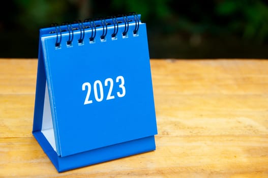 2023 blue desk calendar on wooden table background. New year concept.