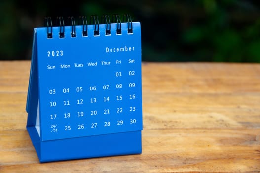 August 2023 blue desk calendar on wooden table background with customizable space for text.