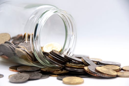 Close up of coins in a jar on white background with customizable space for text or ideas. Business and investment concept.