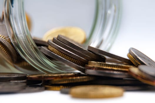 Close up of coins in a jar on white background with customizable space for text or ideas. Business and investment concept.