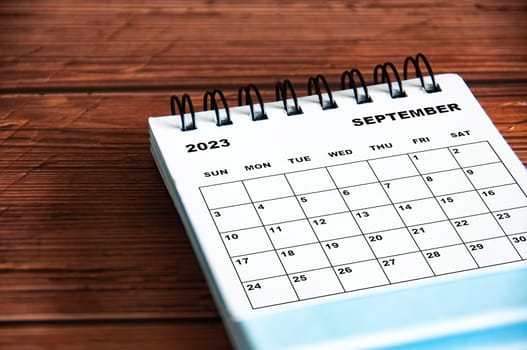 September 2023 white desk calendar on wooden table background.
