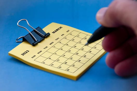 February 2023 calendar on notepad with hand holding black pen background. Appointment concept