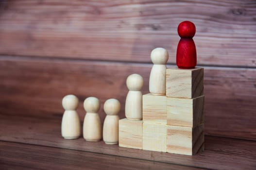 Red figure on top of wooden blocks leading other figures to success. Leadership and business culture concept.