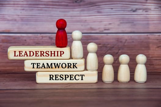 Leadership concept - Leadership, teamwork and respect text on wooden blocks with red and white doll figure on wooden cover background.
