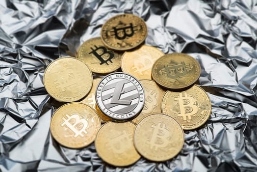 Bitcoin and cryptocurrency investing symbol concept. Litecoin and bitcoin on silver crumpled foil background. Trading on the cryptocurrency exchange. Trends in bitcoin exchange rates.