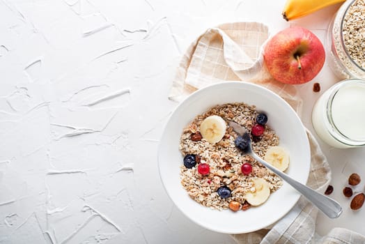 A bowl of dry granola and muesli served with fresh fruit and nuts. Oatmeal plate. Healthy food, diet. Top view.
