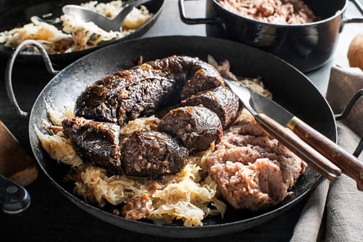 Bloody sausage morcilla, stewed sauerkraut and mashed potato with beans close up. Traditional Slovenian dish with roasted bloody sausage