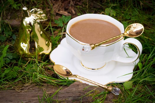 A cup of capuccino in white cup on grass, vintage style