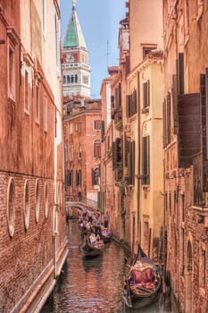 Gondoloas drift down thre canals with St. Marks, Campanile Tower, in the background, Venice, Italy.