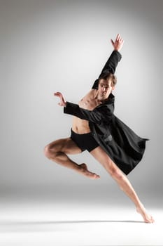 The young attractive modern ballet dancer in black jacket over white background.