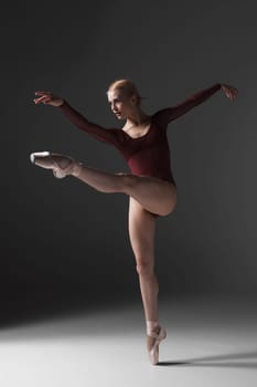 young beautiful modern style dancer posing on a studio gray background