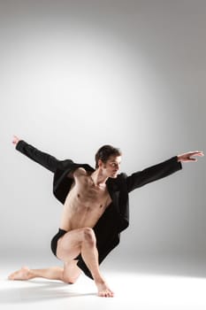 The young attractive modern ballet dancer in black jacket over white background.