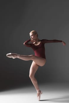 young beautiful modern style dancer posing on a studio gray background