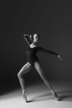 young beautiful modern style dancer posing on a studio gray background. black and white photo