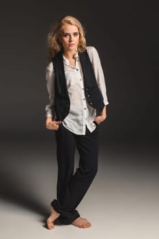 Beauty blond woman  in a black suit and white shirt on a gray background. Portrait in full growth