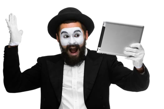 Man with a face mime working on a laptop isolated on a white background. concept of thinking in business