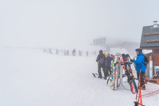 El Tarter, Andorra, Jan 2020 Skiers and snowboarders exiting ski lift on a top of a mountain, low visibility due to heavy mist, fog or low cloud
