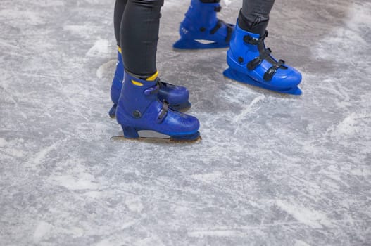 Children enjoy skating on ice. Blue ice skates detail