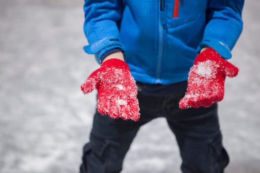 Child boy show his gloves full of ice. Recreational ice rink concept