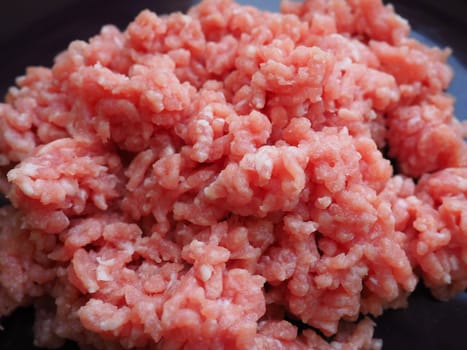 Minced meat on a purple ceramic large plate. Delicious fresh ground meat for making cutlets, steaks, hamburgers, meatballs. Pork semi-finished products.