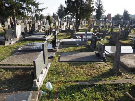 Sremska Mitrovica, Serbia, February 25, 2021. Christian city modern cemetery. Graves with stone monuments and crosses. Granite headstones. Crypt or chapel. Funeral or Halloween theme.