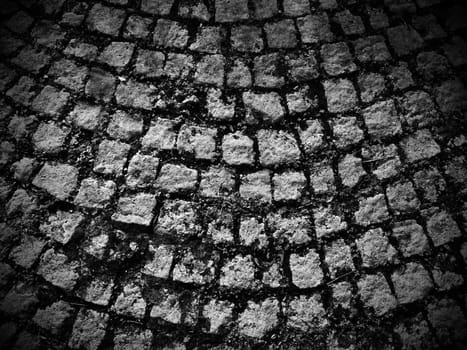 Neatly laid out old paving stones. Pavement on the square of the old town. Square and rectangular stones on the ground, covered with moss and lichens.