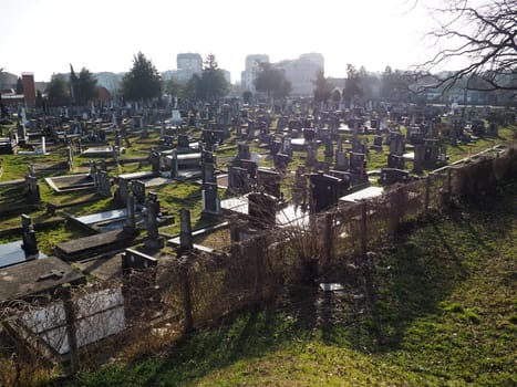 Sremska Mitrovica, Serbia, February 25, 2021. Christian city modern cemetery. Graves with stone monuments and crosses. Granite headstones. Crypt or chapel. Funeral or Halloween theme.
