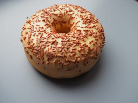 A doughnut or donut. A type of leavened fried dough. Sweet snack that can be homemade or purchased in bakeries, supermarkets, food stalls. Delicious pie with light icing on gray background.