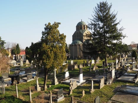 Sremska Mitrovica, Serbia, February 25, 2021. Christian city modern cemetery. Graves with stone monuments and crosses. Granite headstones. Crypt or chapel. Funeral or Halloween theme.