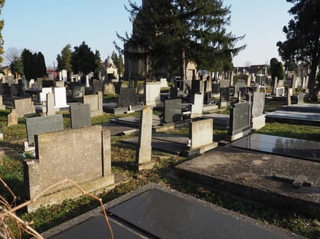 Sremska Mitrovica, Serbia, February 25, 2021. Christian city modern cemetery. Graves with stone monuments and crosses. Granite headstones. Crypt or chapel. Funeral or Halloween theme.