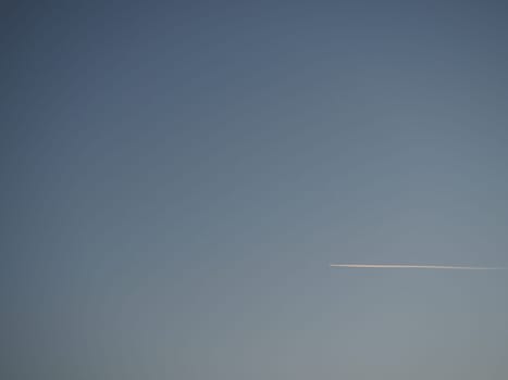 plane and trail in the evening sky blue. Abstract background on a space or aero theme. Color gradient.
