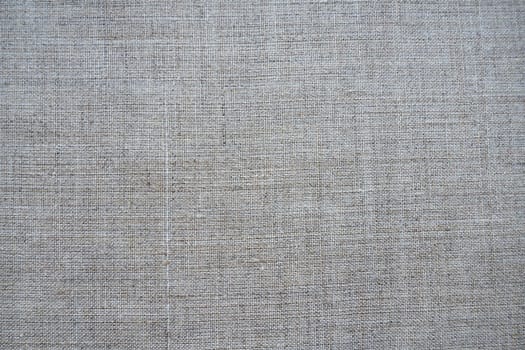 Fabric texture background. Gray fabric with weave. Natural slightly wrinkled look of the material. Uniform copy space background. Cotton, canvas or woolen thin fabric laid evenly on the surface