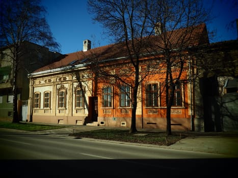Sremska Mitrovica, Serbia, February 15, 2021. Facade of old houses of the 19-20 century. Historical architectural value. Ornate stucco houses in the streets of the city. Birch trees on the lawn