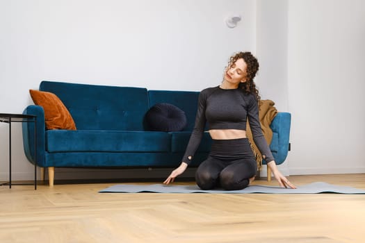 Young woman warming up neck muscles before doing fitness exercises at home