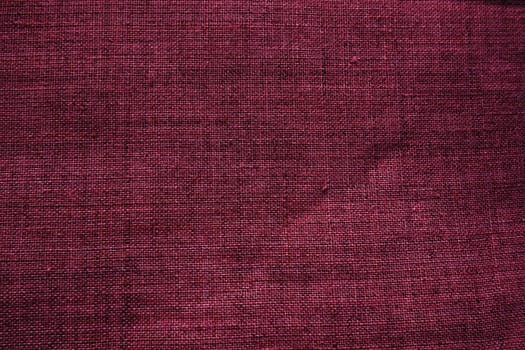 Fabric texture background. Burgundy purple fabric with weave. Natural slightly wrinkled look of the material. Uniform copy space background. Cotton, canvas or woolen thin fabric laid on the surface