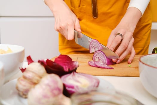 Closeup view of female hands cutting onion into slices