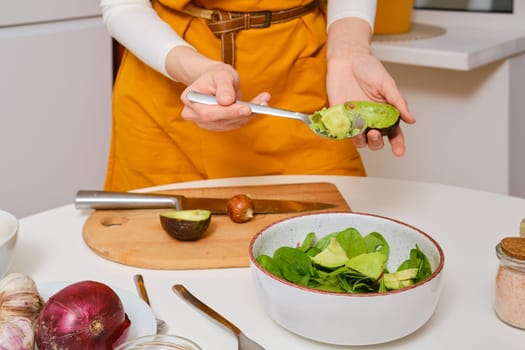 Unrecognizable woman removing avocado out of the shell with spoon closeup