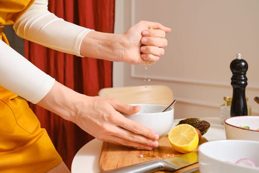 Unrecognizable woman squeezing juice of lemon in vegetable salad
