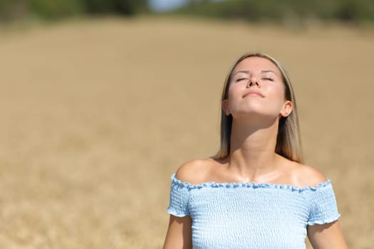 Front view portrait of a woman breathing fresh air in a golden field