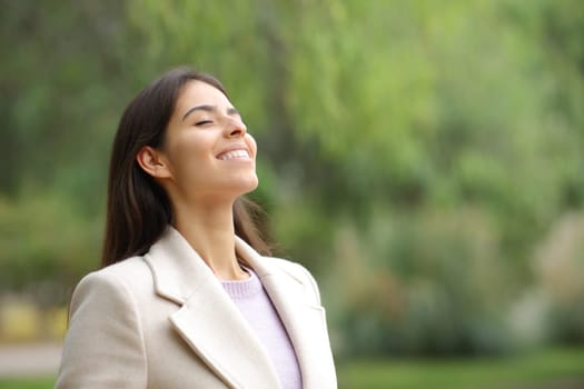 Happy woman in winter breaths fresh air in a park