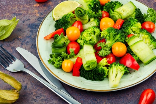 Vitamin raw salad with broccoli, bell pepper, tomato, cucumber and physalis.