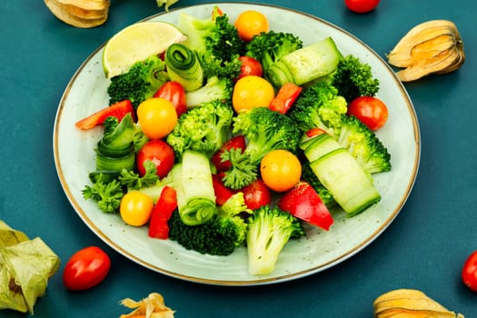 Vitamin raw salad with broccoli, bell pepper, tomato, cucumber and physalis.