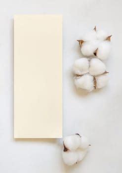 Blank paper card with cotton flowers top view on white, mockup. Romantic scene with wedding menu or invitation card. Bohemian pastel greeting or wedding vertical card