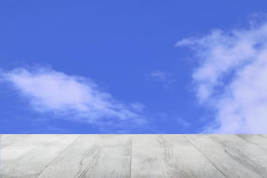 Empty wooden table with abstract blurred natural cloudy blue sky background. Space for your food and product display montage.