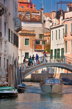 Boaters motor down the many canals of Venice, Italy on a hot summer day.