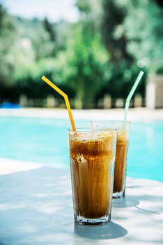 Two glass of iced frappe near the swimming pool.