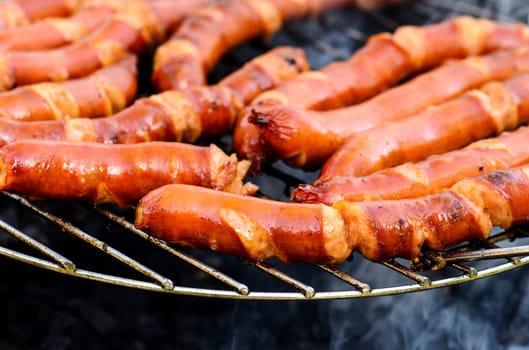 Grilled sausages bbq on outdoor picnic. Fresh tasty sausage preparing for summer barbecue.